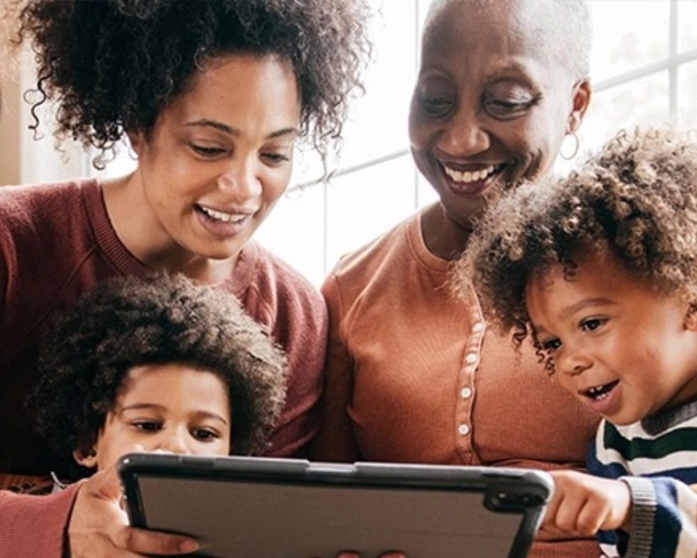 an older woman, a younger woman, and two children gathered around a tablet device