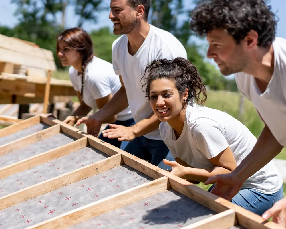A group of people working together to lift a framed wall