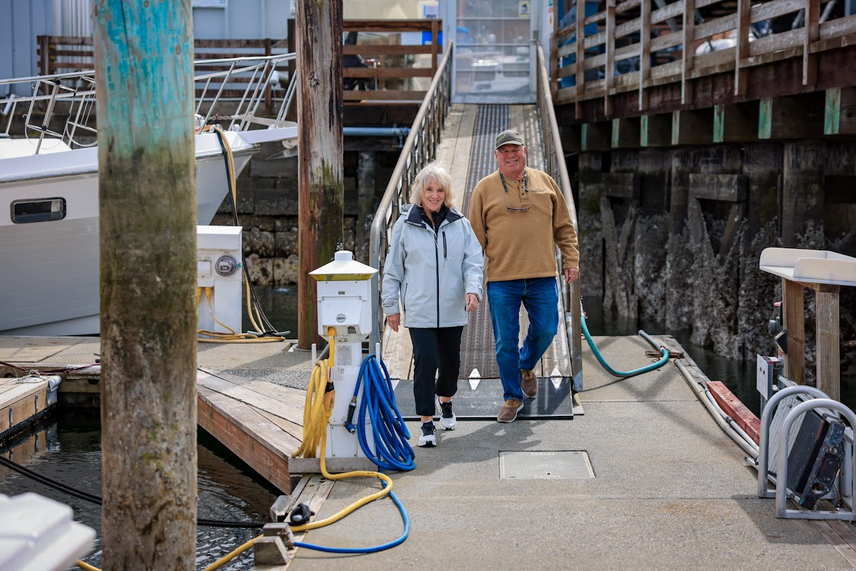 Lee and Carol Snyder walking down a ramp onto a boat dock.